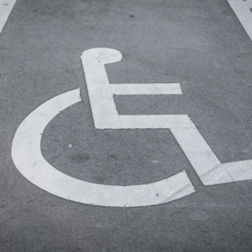 L09 – Sostegno alle famiglie con persone con disabilità Simbolo internazionale di accessibilità su un parcheggio riservato alle persone con disabilità