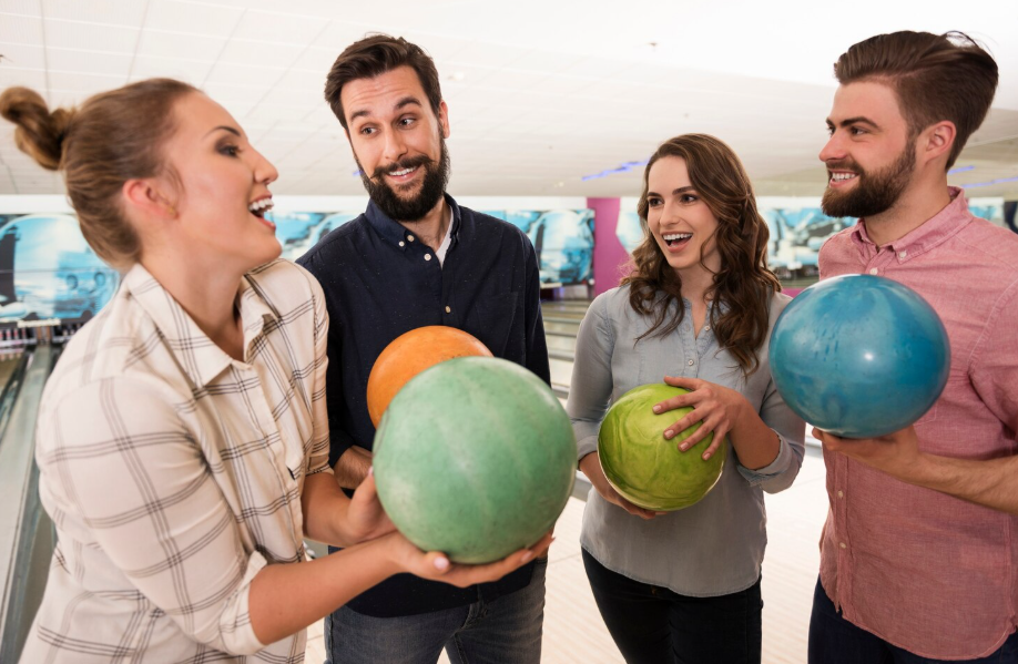 Quattro persone con palle da bowling in una sala da bowling